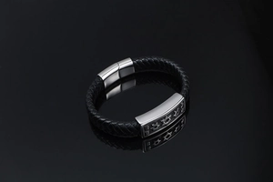 Close-up of black braided leather bracelet featuring silver stars on metal plate
