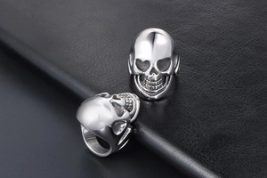 Detail shot of vintage punk skull rings with heart-shaped eyes on black leather