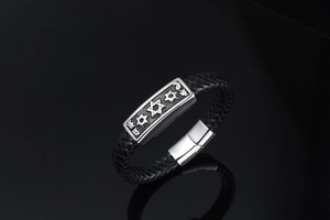 Detailed macro view of woven black leather bracelet with engraved star metal plate