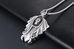 Gothic skull pendant necklace with bat wings detail on black leather background