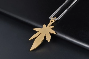 Gros plan du pendentif feuille d'érable dorée avec texture brossée sur chaîne argent