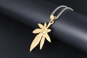Vue détaillée du pendentif feuille d'érable dorée avec étoile sur chaîne épi argentée