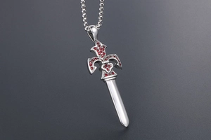 Macro shot of silver sword pendant with red zircon stones and detailed engraving