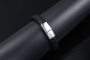 Close-up of a men's black braided leather bracelet with a silver polished magnetic clasp