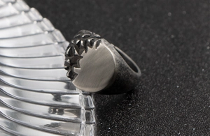 Macro detail of men's vintage steel ring with half-polished and rocky textured surface