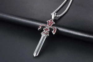 Macro view of sword pendant with red rhinestones and fleur-de-lis on black leather