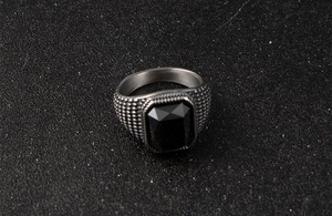 Gros plan d'une bague pour homme en acier inoxydable avec une grande pierre noire carrée