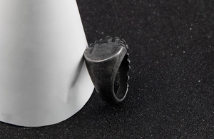 Macro view of vintage stainless steel ring with rustic finish on a white display stand