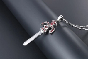 Detailed close-up of a silver sword pendant with red stones on a dark base