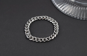 Macro shot of silver stainless steel Cuban link bracelet on a textured black surface