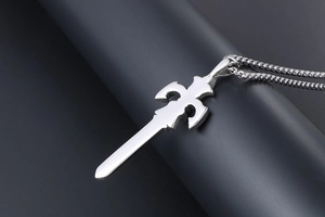 Detail shot of a silver sword pendant with gothic hilt pattern on a cylindrical stand