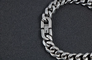 Detail of polished stainless steel Cuban link bracelet with secure clasp on leather