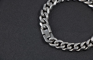 Macro detail of silver stainless steel Cuban link bracelet with modern square clasp