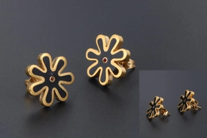 Detailed macro view of gold-plated daisy stud earrings with black enamel and red zircon