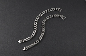 Detailed top view of two titanium steel Cuban link bracelets with polished flat clasps