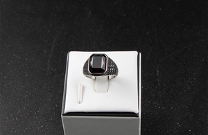 Macro d'une bague vintage homme en acier avec zircon rouge sur un support blanc