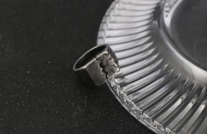 Macro shot of vintage titanium steel ring with cracked texture on a textured glass surface
