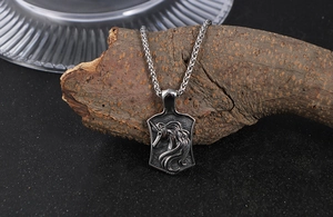 Detail view of vintage titanium steel unicorn shield pendant on rustic wood texture