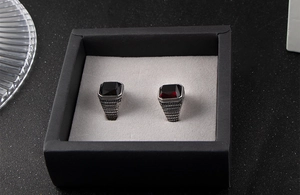 Détail de bagues vintage en acier avec gemmes rouges et noires dans un écrin