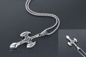 Close-up of a silver vintage cross pendant with intricate floral engravings and box chain