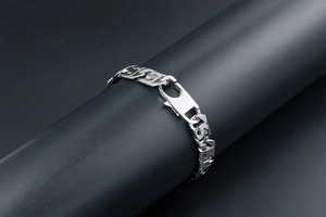 Détail macro du bracelet gourmette en acier poli avec maillons en S et fermoir mousqueton