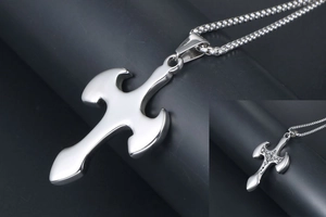 Macro view of stainless steel cross pendant featuring intricate vintage relief engraving