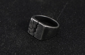 Close-up of vintage titanium steel ring featuring industrial cracked texture and dark finish