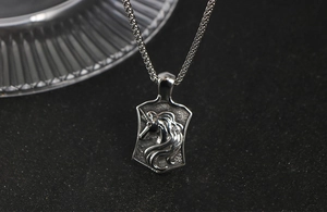 Macro shot of silver unicorn shield pendant with embossed detail on wheat chain