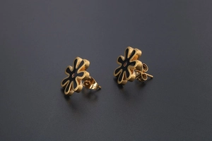Macro shot of titanium steel daisy earring with gold plating and black enamel petals