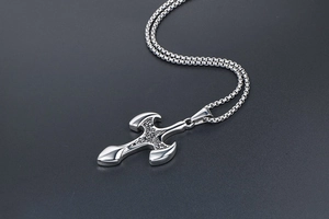 Macro shot of silver titanium cross pendant with vintage gothic patterns and square chain