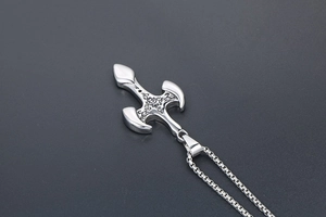 Macro detail of silver titanium cross pendant with vintage floral gothic engraving