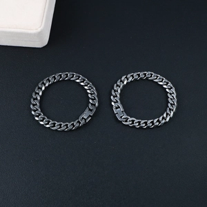 Polished gunmetal gray curb chain bracelets for men on a textured leather background