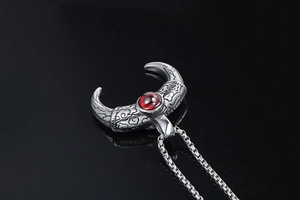 Detail of Mayan-style titanium steel pendant with red gemstone and vintage relief patterns