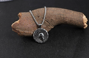 Détail du pendentif casque spartiate rétro en acier sur chaîne torsadée et socle bois