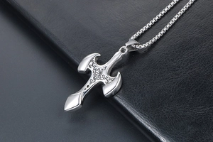 Detailed close-up of a men's silver steel cross pendant with intricate vine engraving