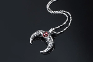 Macro shot of silver crescent horn pendant with vintage patterns and red center stone