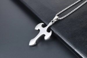 Macro shot of a polished silver titanium cross pendant with sleek curved metal surface