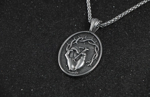 Gros plan du pendentif gothique en acier titane avec main percée d'un clou et couronne d'épines