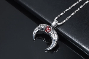 Close-up of titanium steel horn pendant with red gemstone and vintage relief patterns