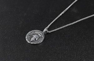 Vue détaillée du pendentif casque spartiate argenté avec sa chaîne à maillons fins