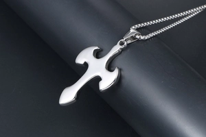 Detailed close-up of a polished titanium steel cross pendant with high-gloss mirror finish