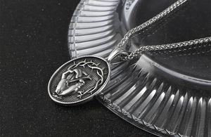 Gros plan du pendentif mains en prière en acier titane avec couronne d'épines et chaîne