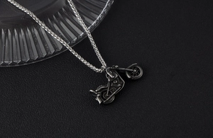 Close-up of retro silver motorcycle pendant with engine details and twisted chain