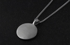 Close-up of brushed silver titanium pendant with textured wheat chain for men