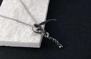 Macro shot of gothic grim reaper scythe pendant on wheat chain with stone background