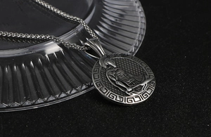 Close-up of vintage steel warrior pendant with Greek key pattern and braided chain