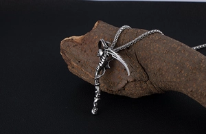 Detailed view of Gothic Grim Reaper scythe pendant with skull handle on textured wood