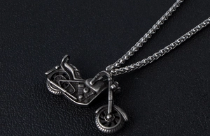 Detailed macro view of vintage silver motorcycle pendant with intricate mechanical texture