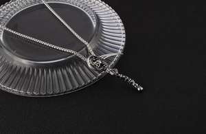Close-up of gothic grim reaper scythe and spine pendant on a steel wheat chain