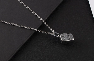 Macro shot of camera pendant necklace featuring a teddy bear silhouette engraving